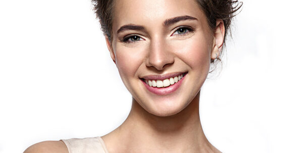 Beautiful smiling woman with clean skin, natural make-up, and white teeth on grey background